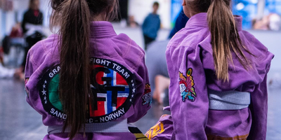 2 barn som sitter med ryggen til, de har kampsport drakt på med logo Sandefjord kampsport